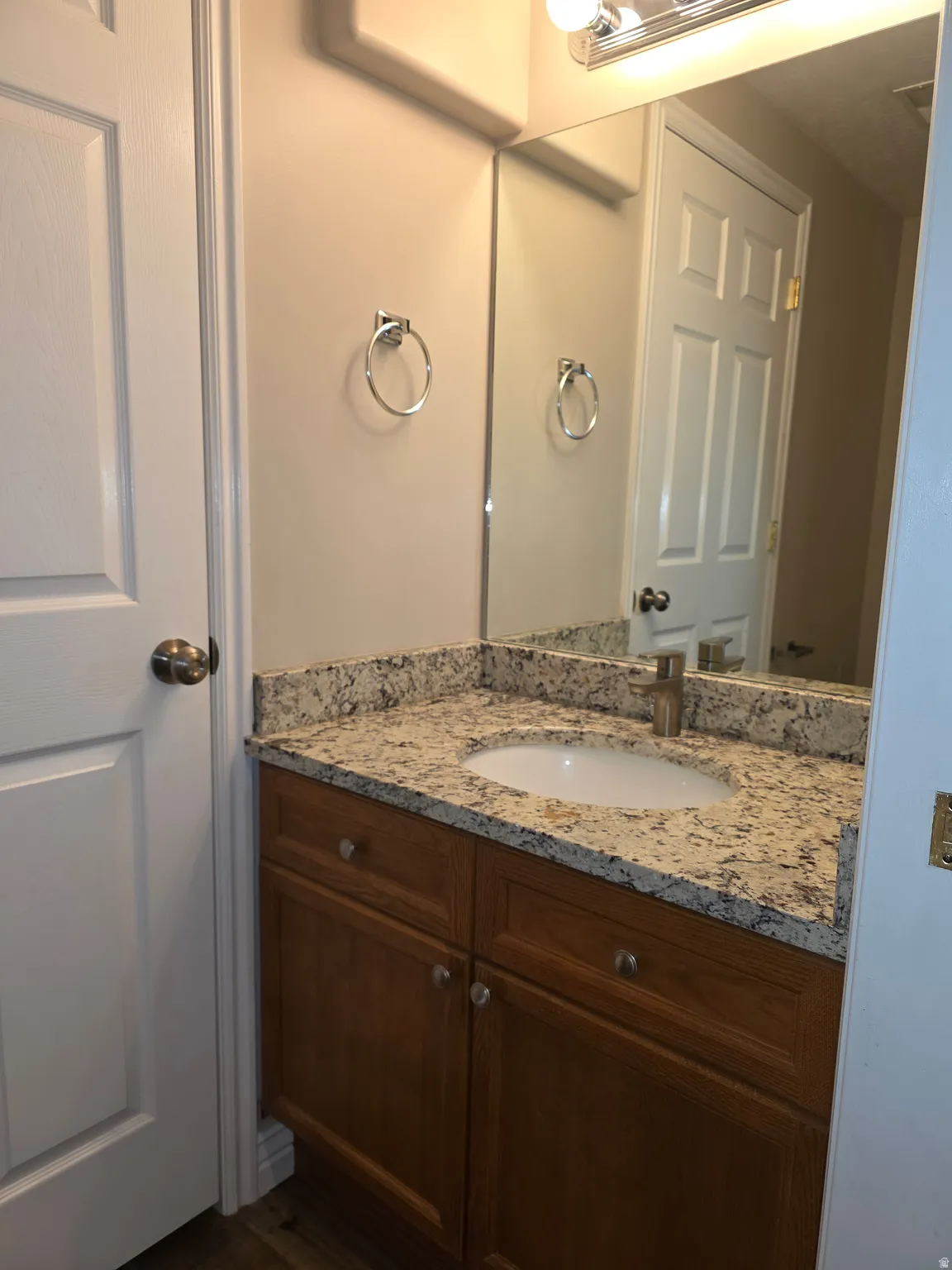 Bathroom vanity featuring wood-finish cabinetry, a granite-style countertop, and an undermount sink
