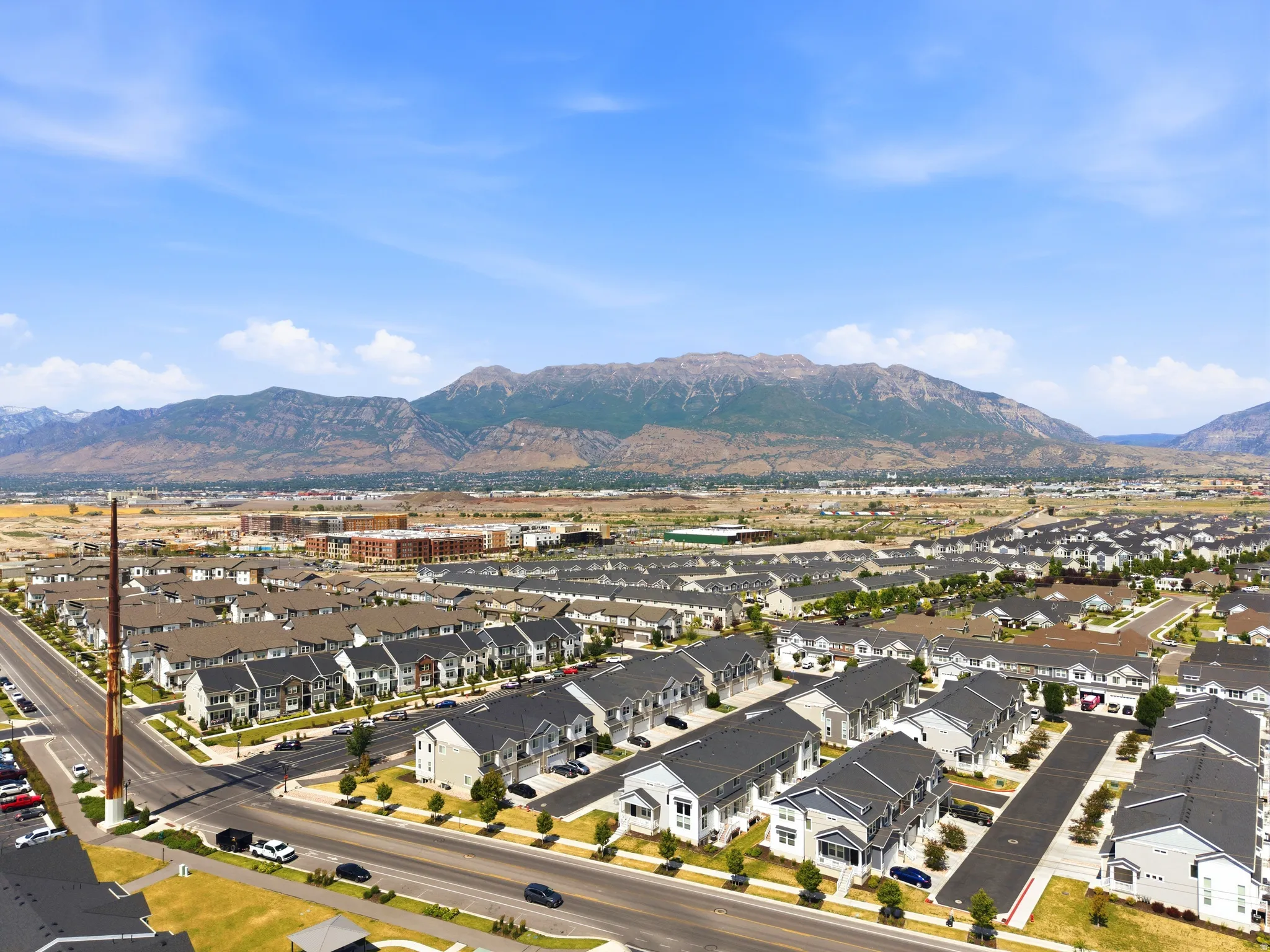 Aerial perspective showcasing a structured residential community with uniform architecture, mountainous scenery, and mature tree-lined streets