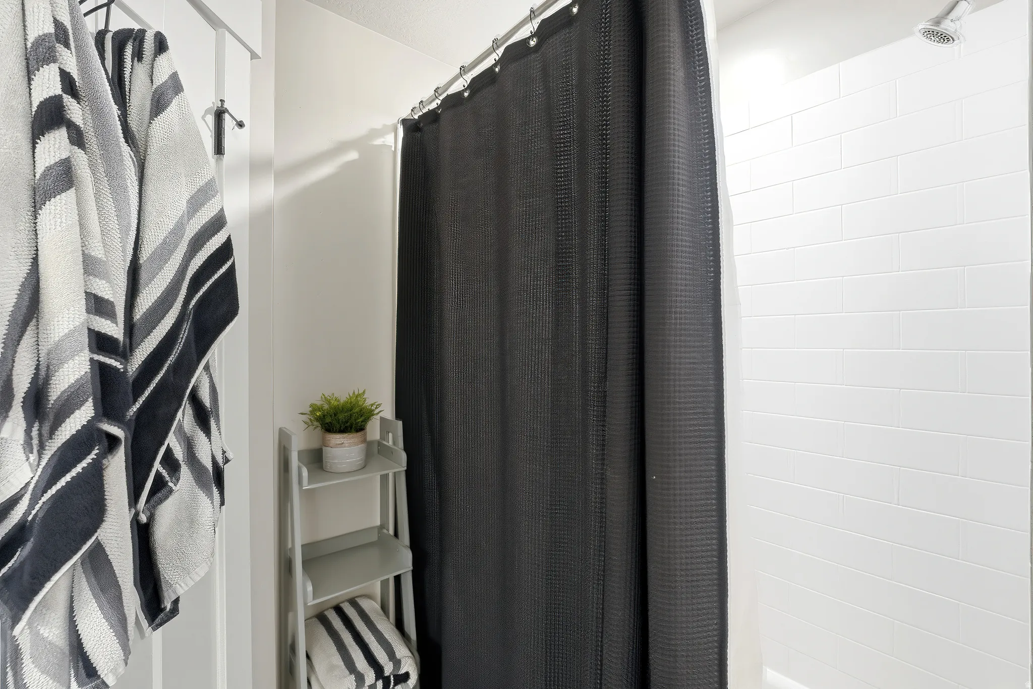 Shower featuring white subway tile surround, a chrome shower head, and a curved shower curtain rod
