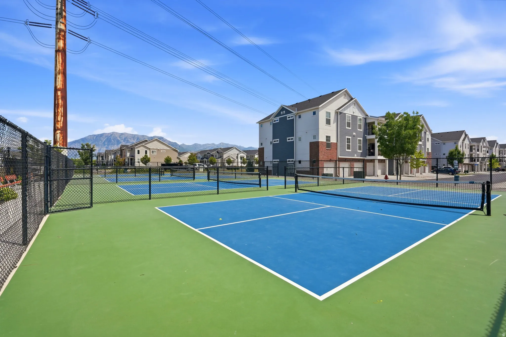 Community tennis courts featuring blue and green hardcourt surfaces and chain-link fencing