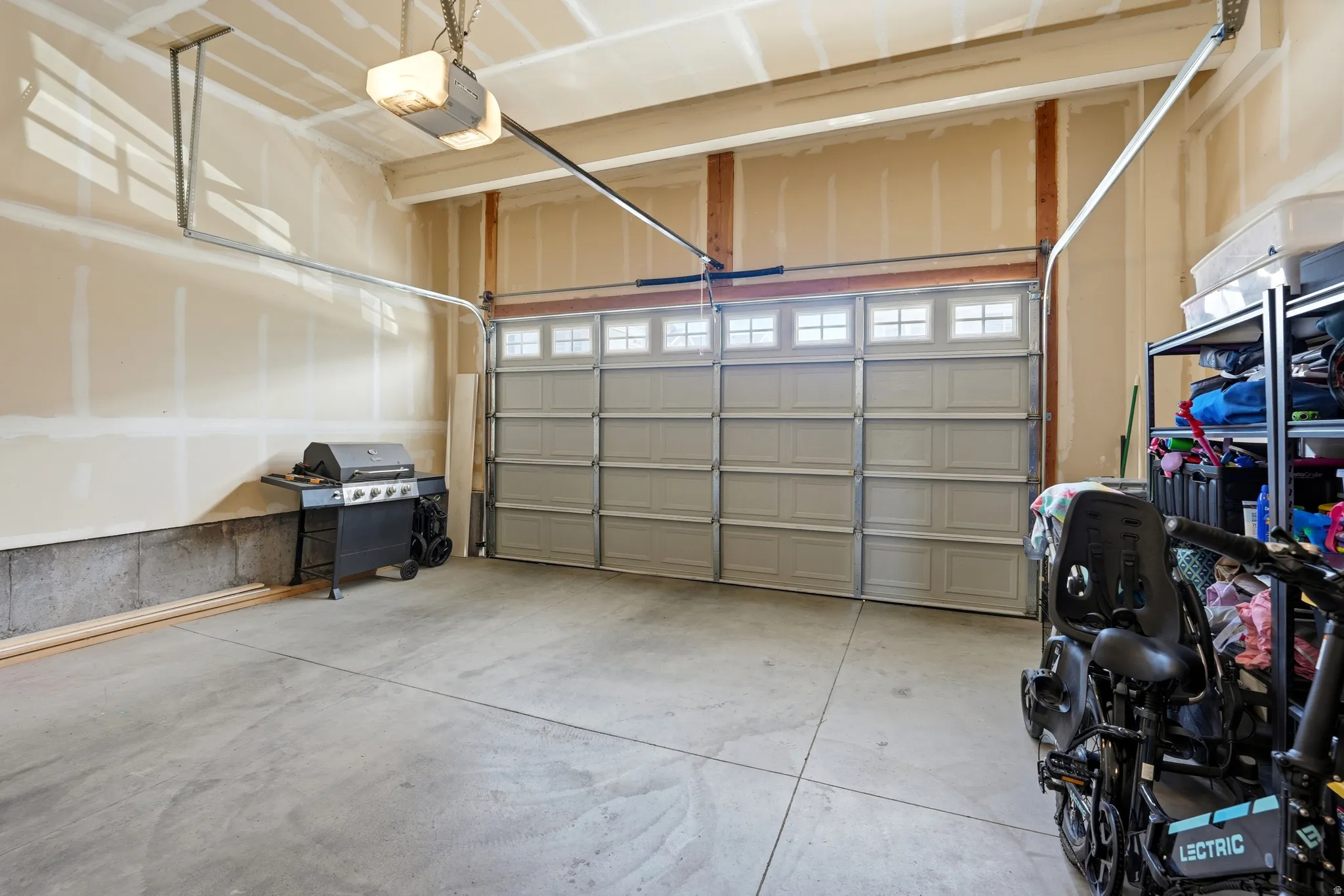Spacious garage featuring a concrete floor, light-colored walls, and a panel garage door with upper window inserts