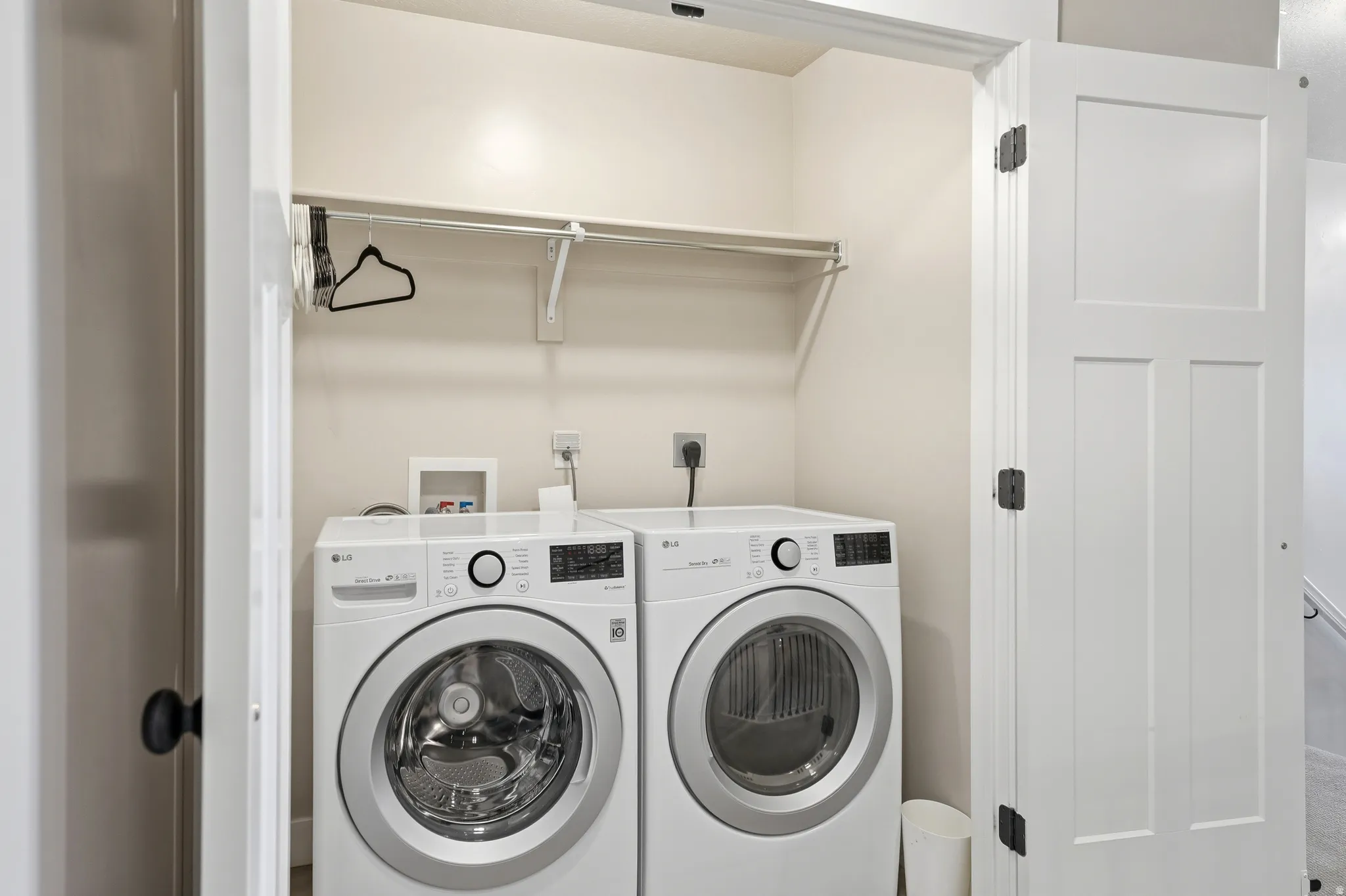 Dedicated laundry area featuring a front-load washer and dryer, a single overhead shelf, and a clothing rod