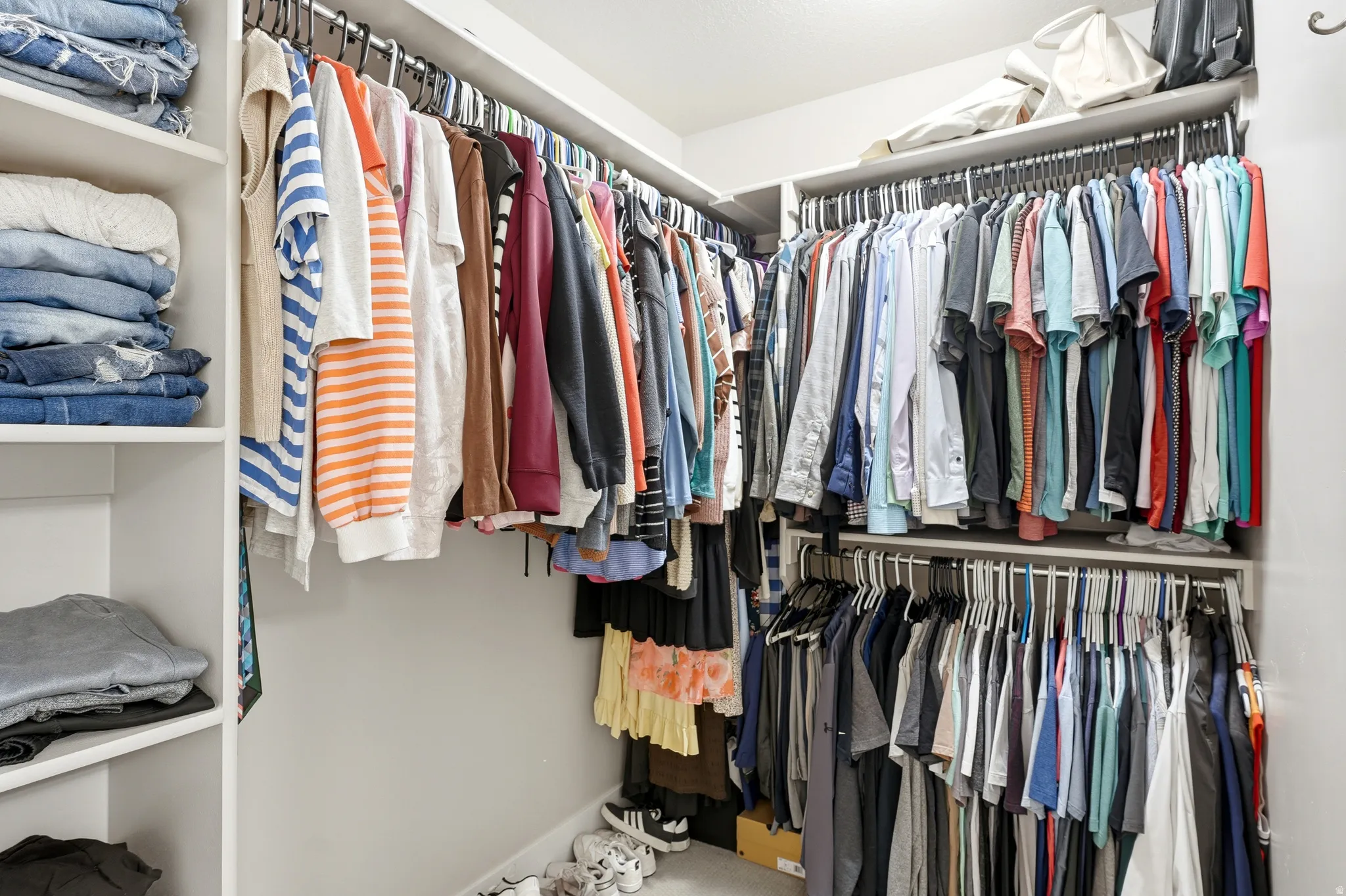 Walk-in closet featuring white shelving, multiple hanging rods, and ample storage space