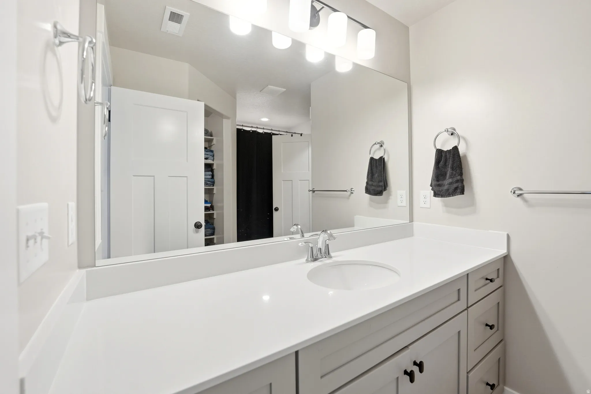 Bathroom vanity with a white countertop and integrated sink, complemented by a large wall-mounted mirror