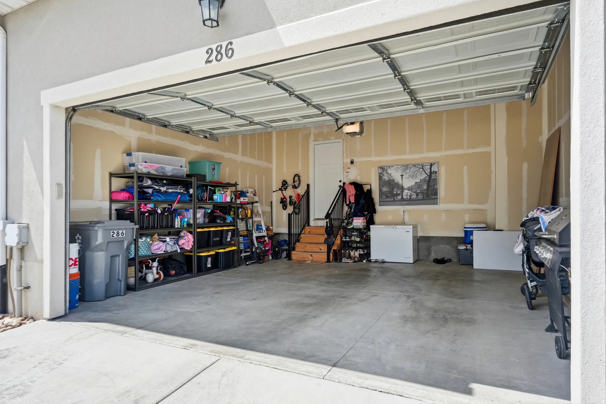 Spacious garage featuring a concrete floor, overhead lighting, and an interior access door