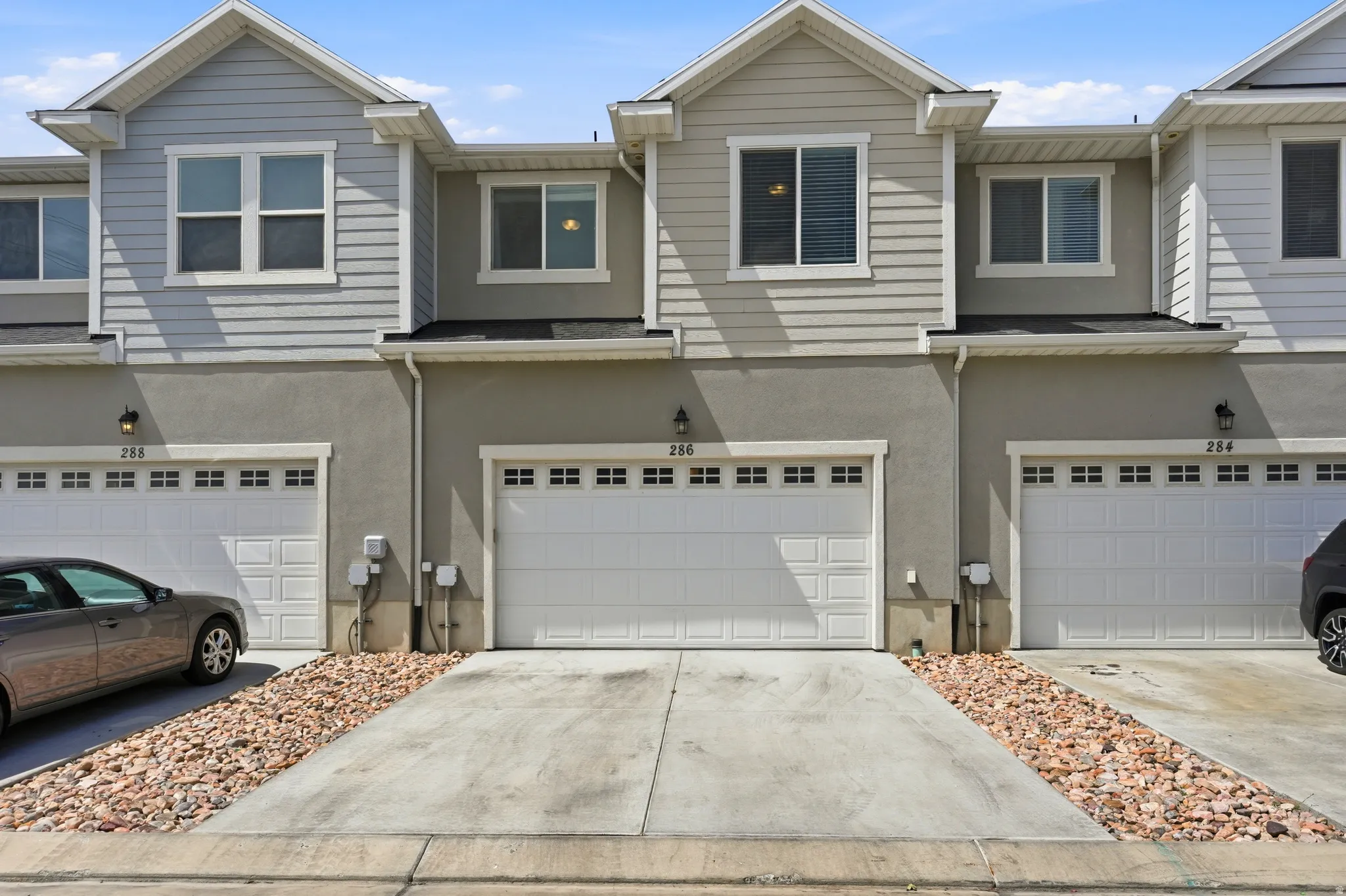 Modern townhome exterior featuring light gray siding and stucco finishes