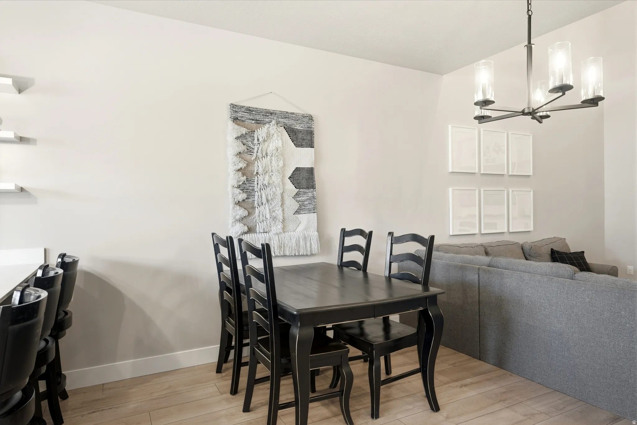 Open-concept interior featuring light-toned walls, wood-finish flooring, and a contemporary multi-light chandelier