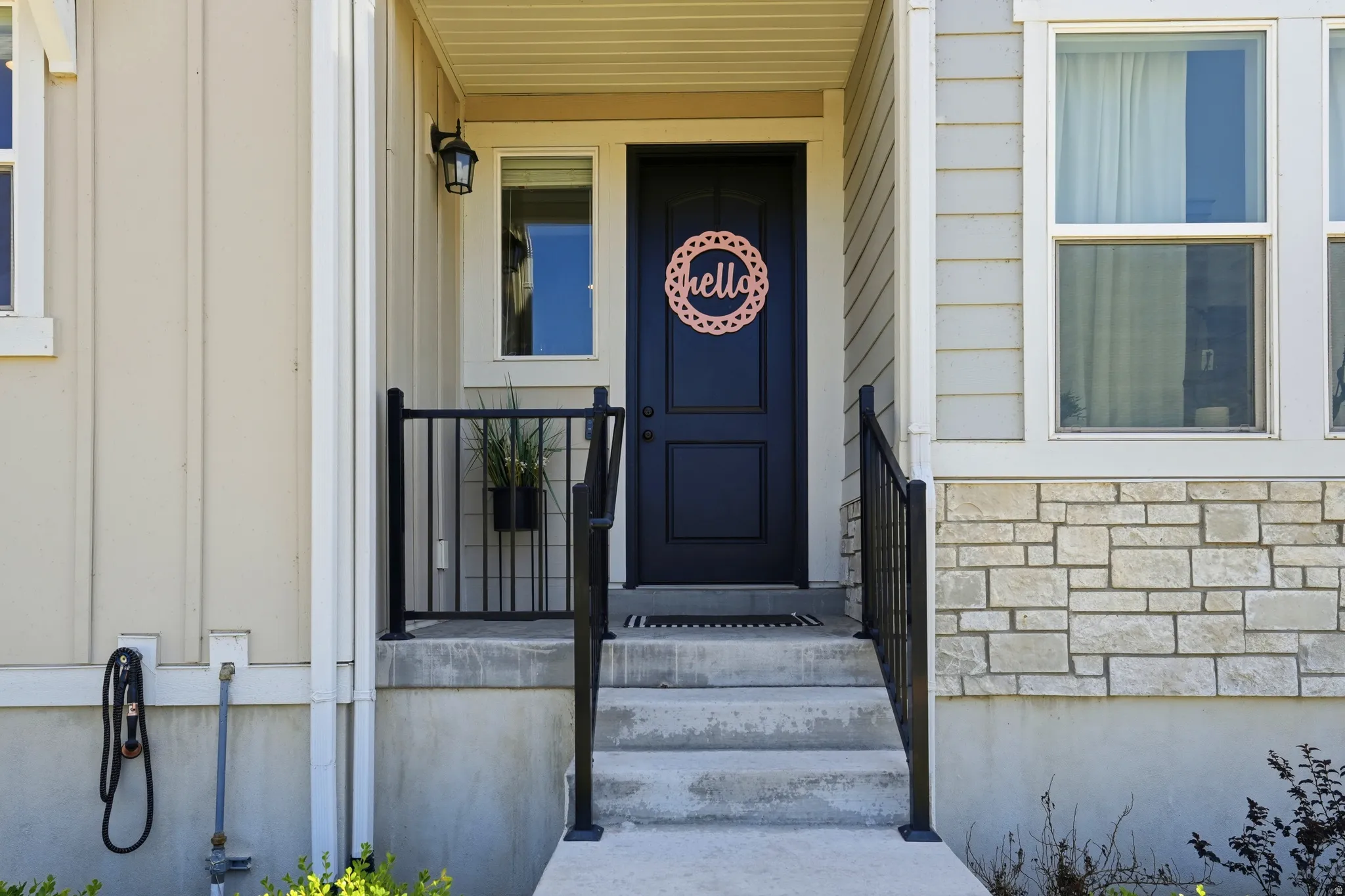 Entryway featuring a dark paneled door, concrete steps, and black metal railings