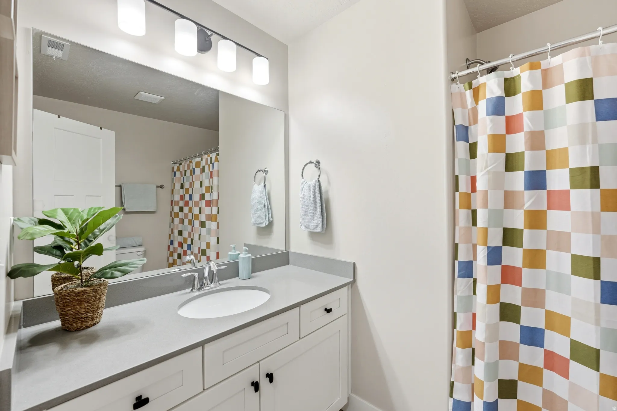 Bathroom vanity featuring a single basin, stainless steel faucet, and a large mirror