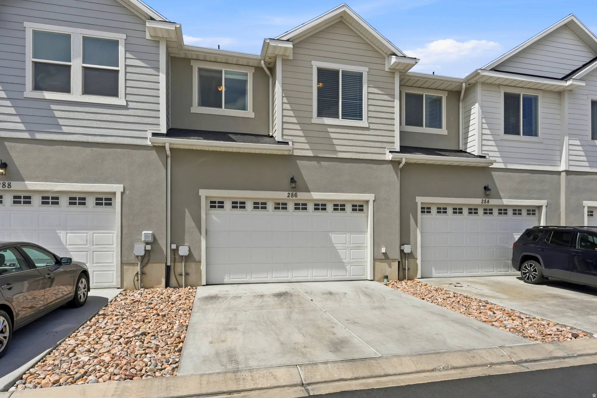 Modern townhome exterior featuring light-colored horizontal siding, stucco finishes, and multiple windows