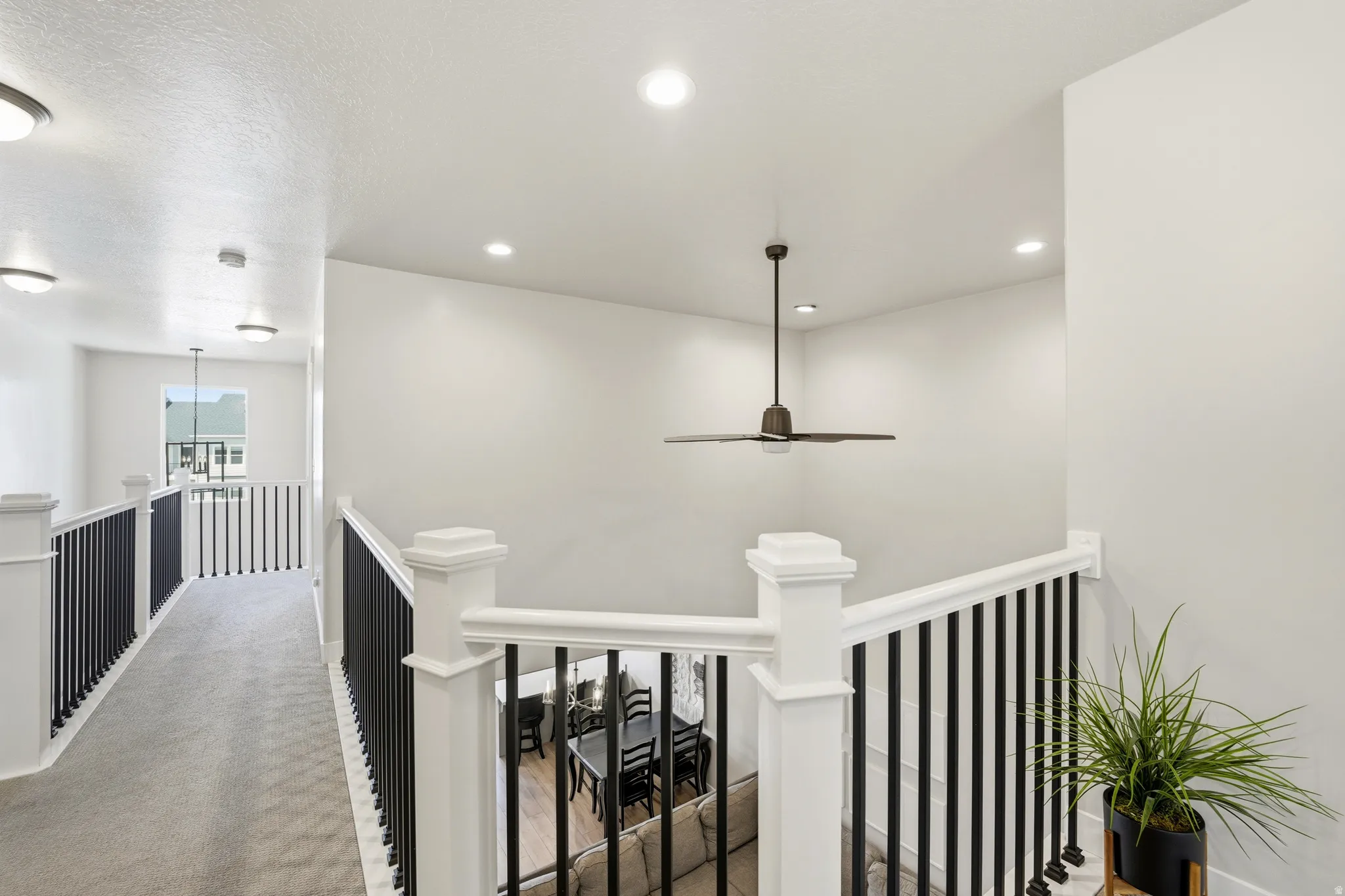 Upper-level landing featuring a carpeted walkway, white walls, and recessed lighting