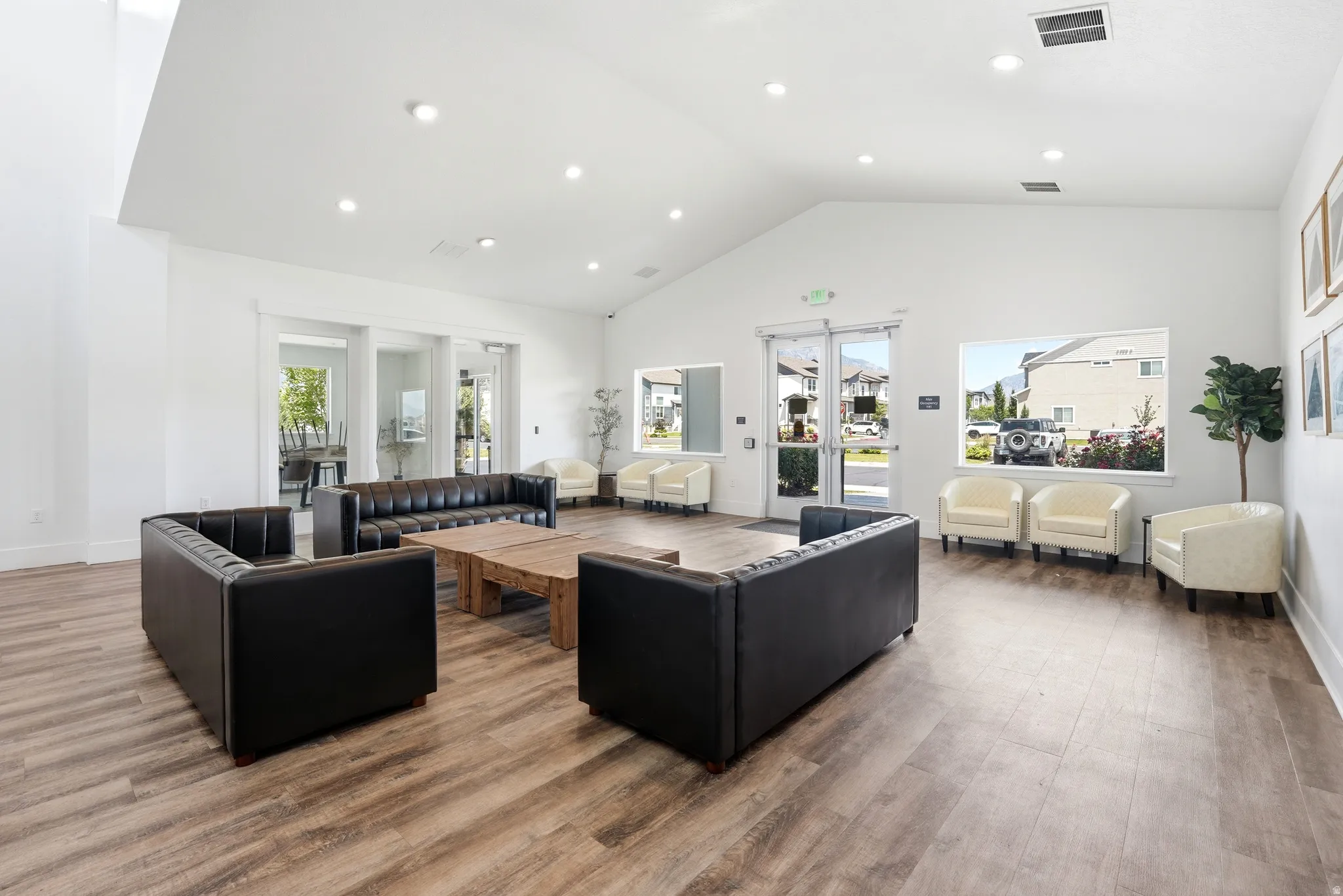 Spacious common area featuring wood-finish flooring, vaulted ceilings, recessed lighting, and multiple windows