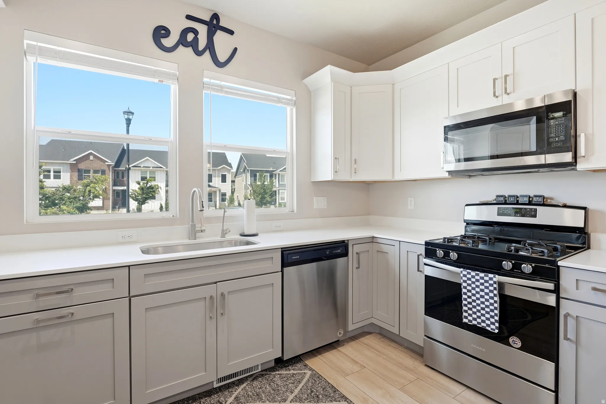 Modern kitchen featuring light grey lower cabinetry, white upper cabinetry, and white countertops