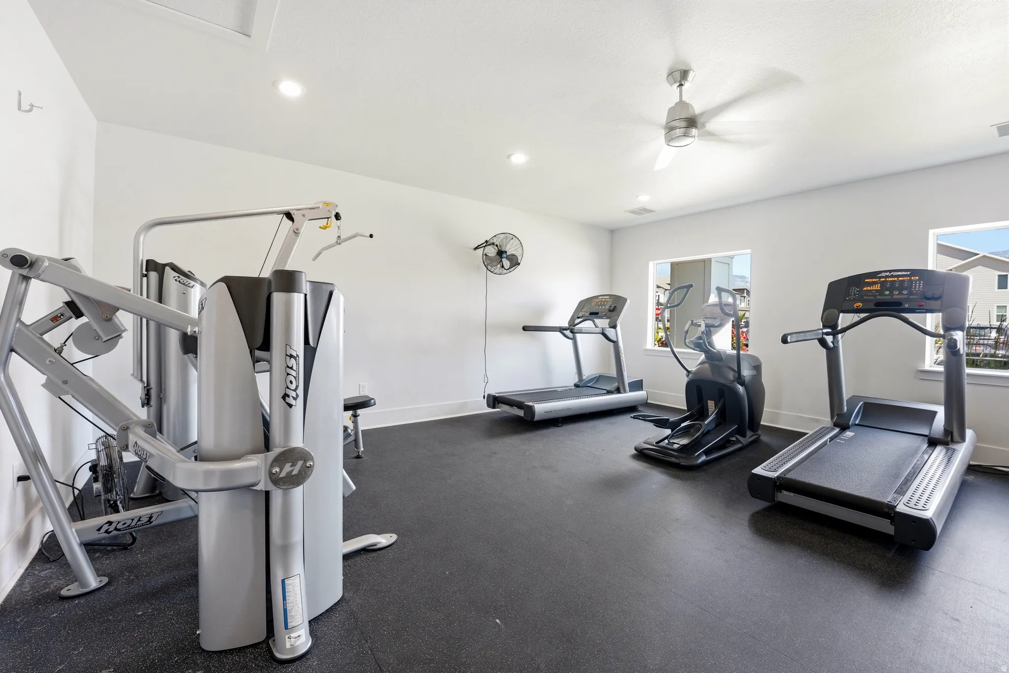 Fitness room with rubber flooring, recessed lighting, ceiling fan, and multiple windows