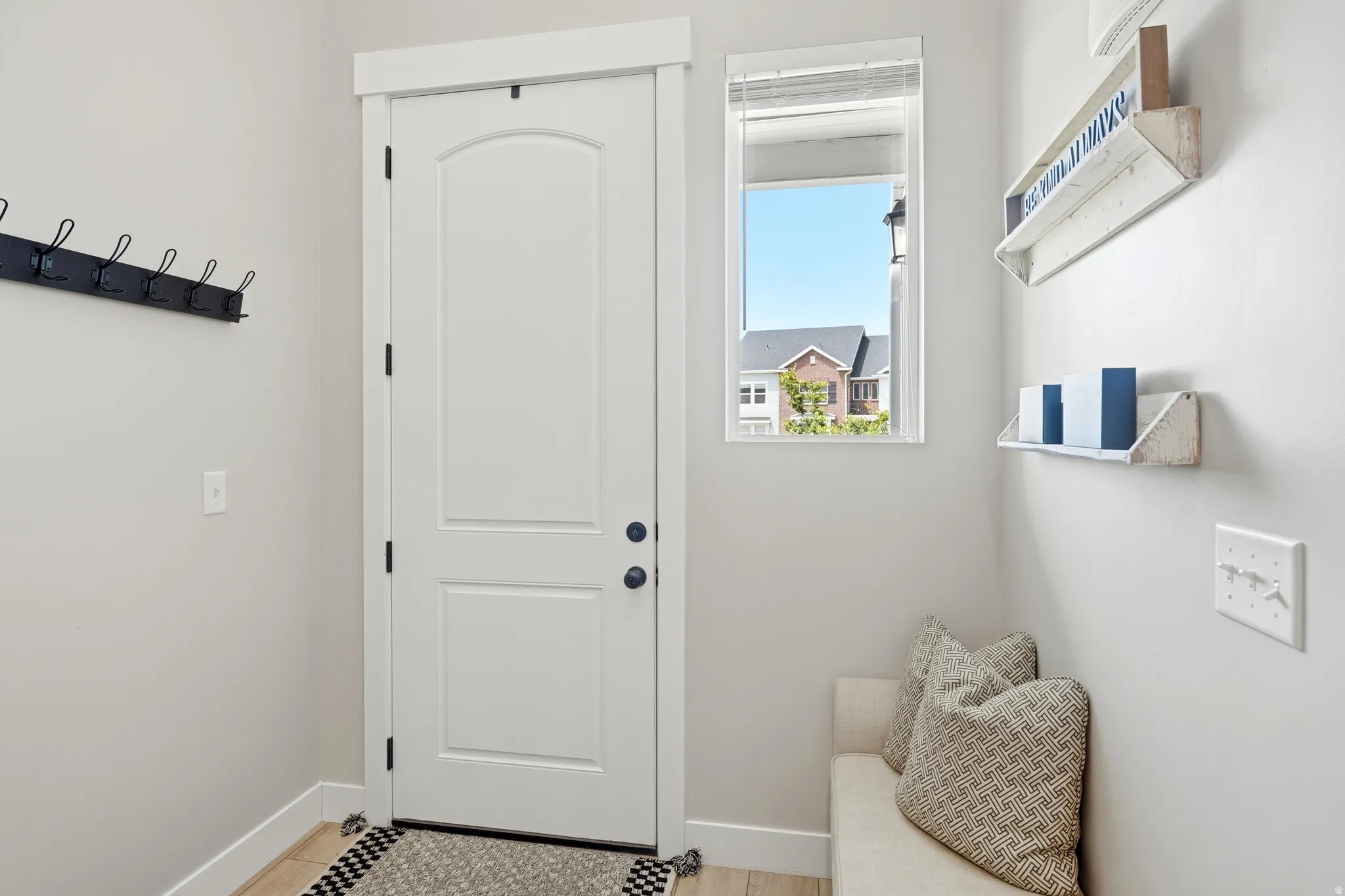 Entryway featuring a white paneled door with dark hardware, a single window, and light-toned walls