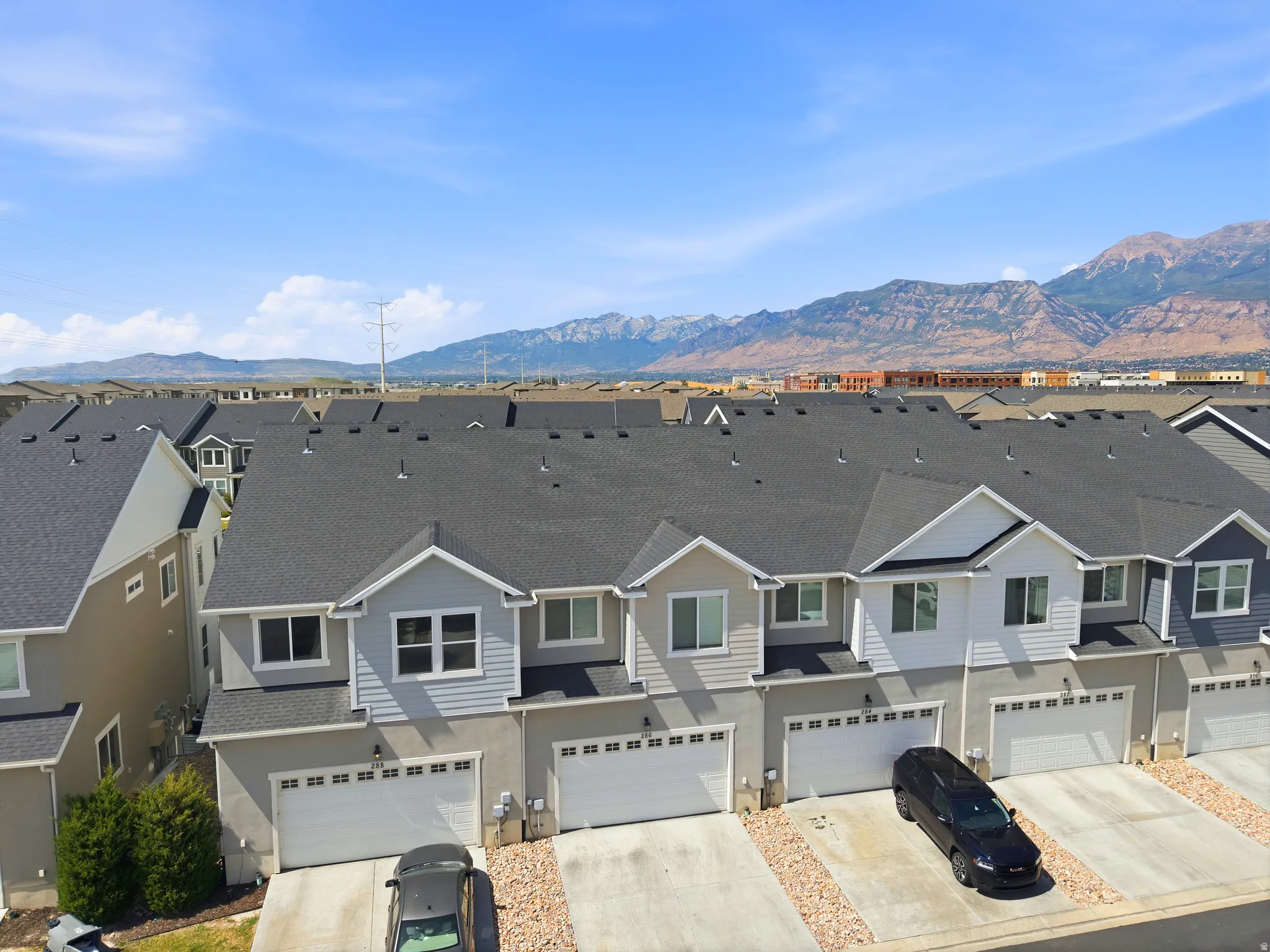Exterior featuring a multi-tone facade with dark grey roofing, white garage doors, and a concrete driveway