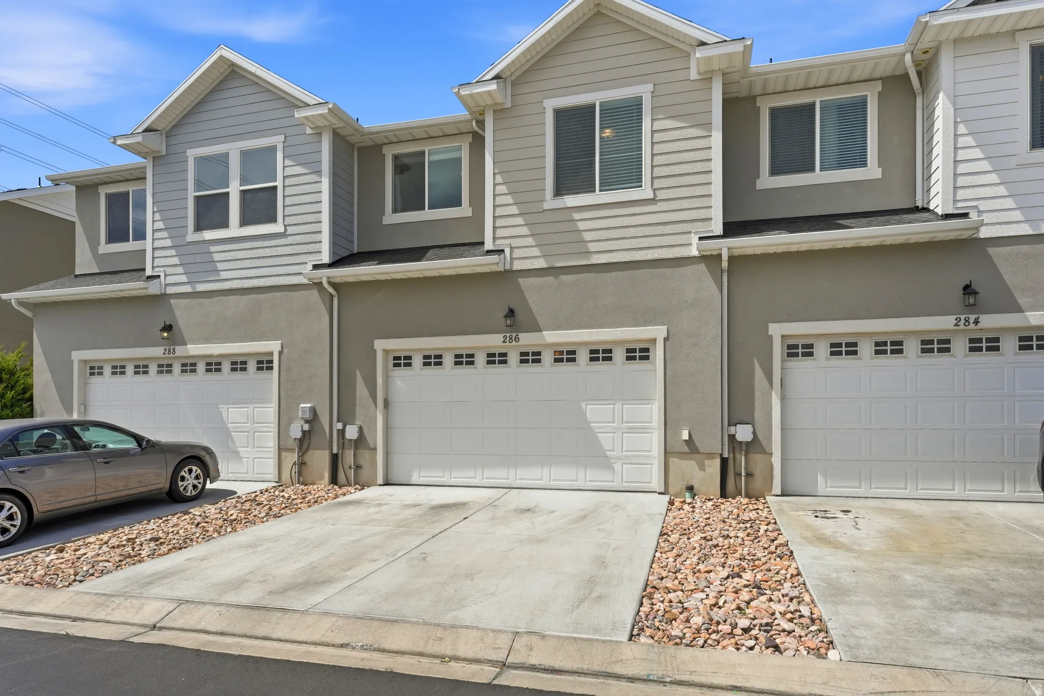 Townhome exterior featuring light gray horizontal siding and stucco, complemented by white trim