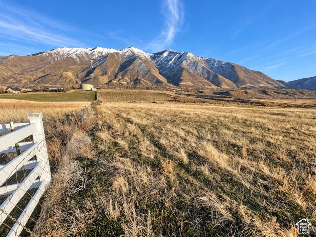 Expansive acreage featuring a white perimeter fence and distant mountains with snow-capped peaks