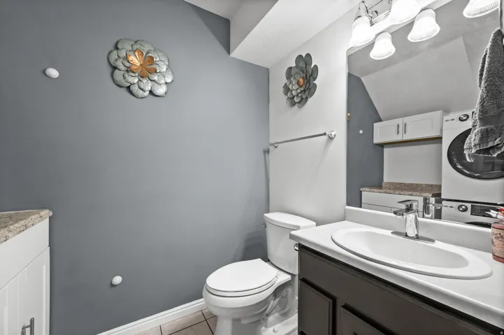 Bathroom featuring a dark wood-finish vanity with an integrated sink, chrome faucet, and overhead bar lighting