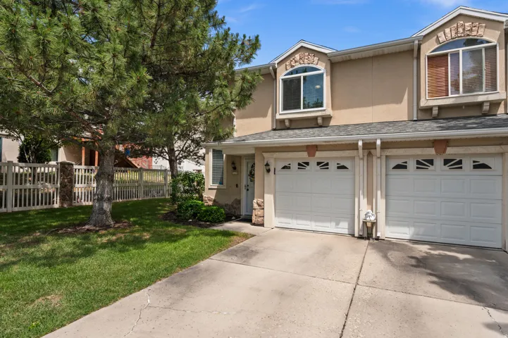 Front exterior featuring two single-car garages, a concrete driveway, and a manicured lawn