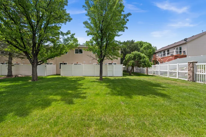 Expansive green lawn with mature trees and perimeter fencing
