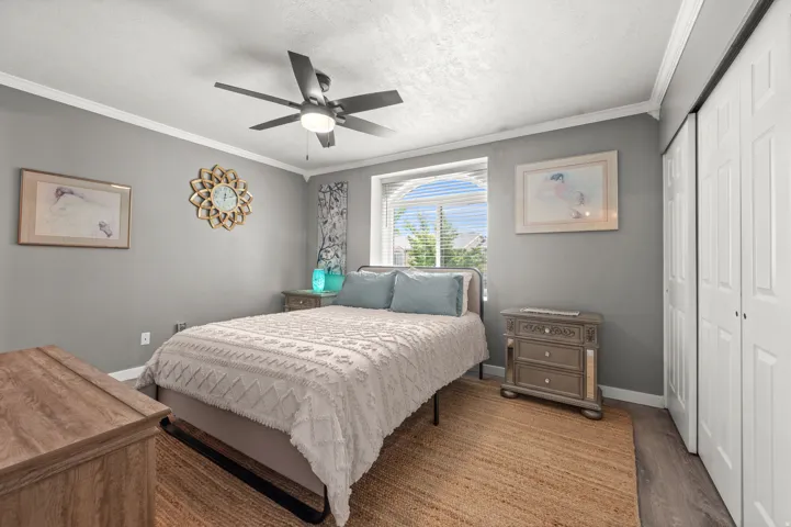 Bedroom with neutral gray walls, crown molding, and a ceiling fan