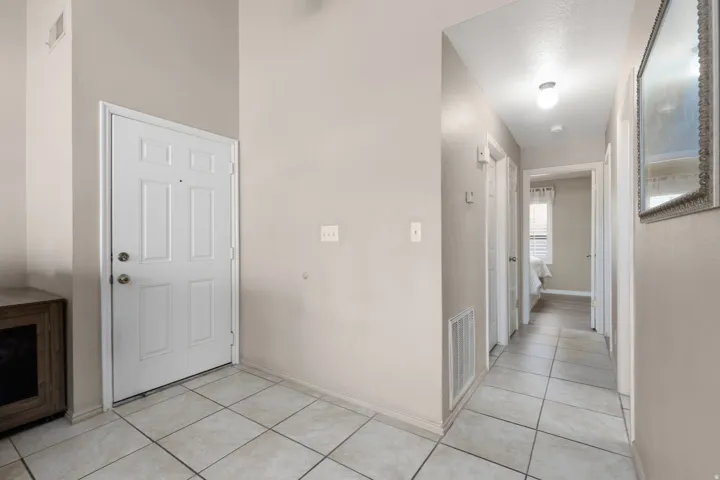 Entry foyer featuring light-colored tile flooring, a paneled entry door, and vaulted ceilings