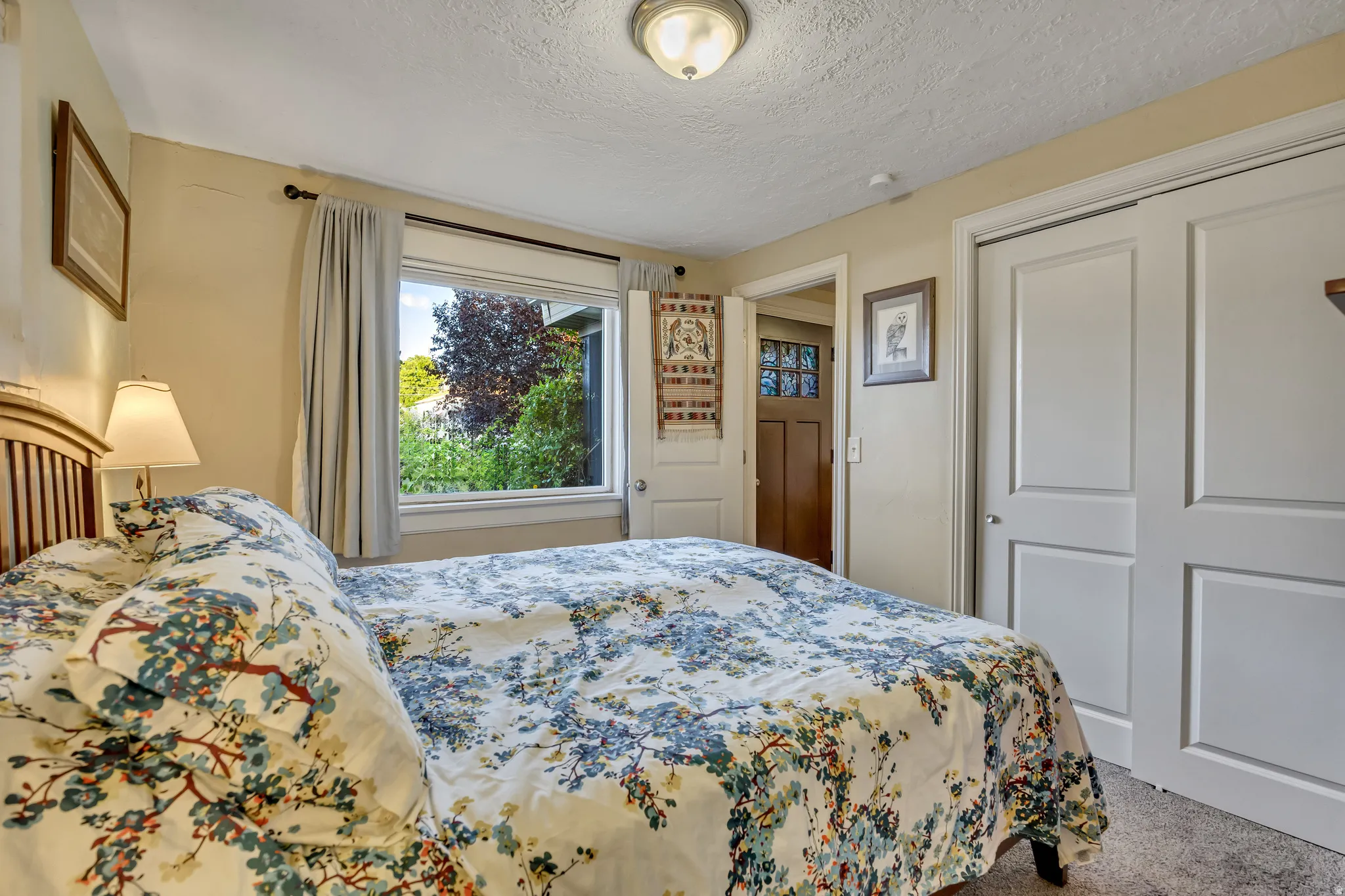 Bright interior room featuring a window with exterior greenery, two panel bi-fold closet doors, and recessed ceiling lighting