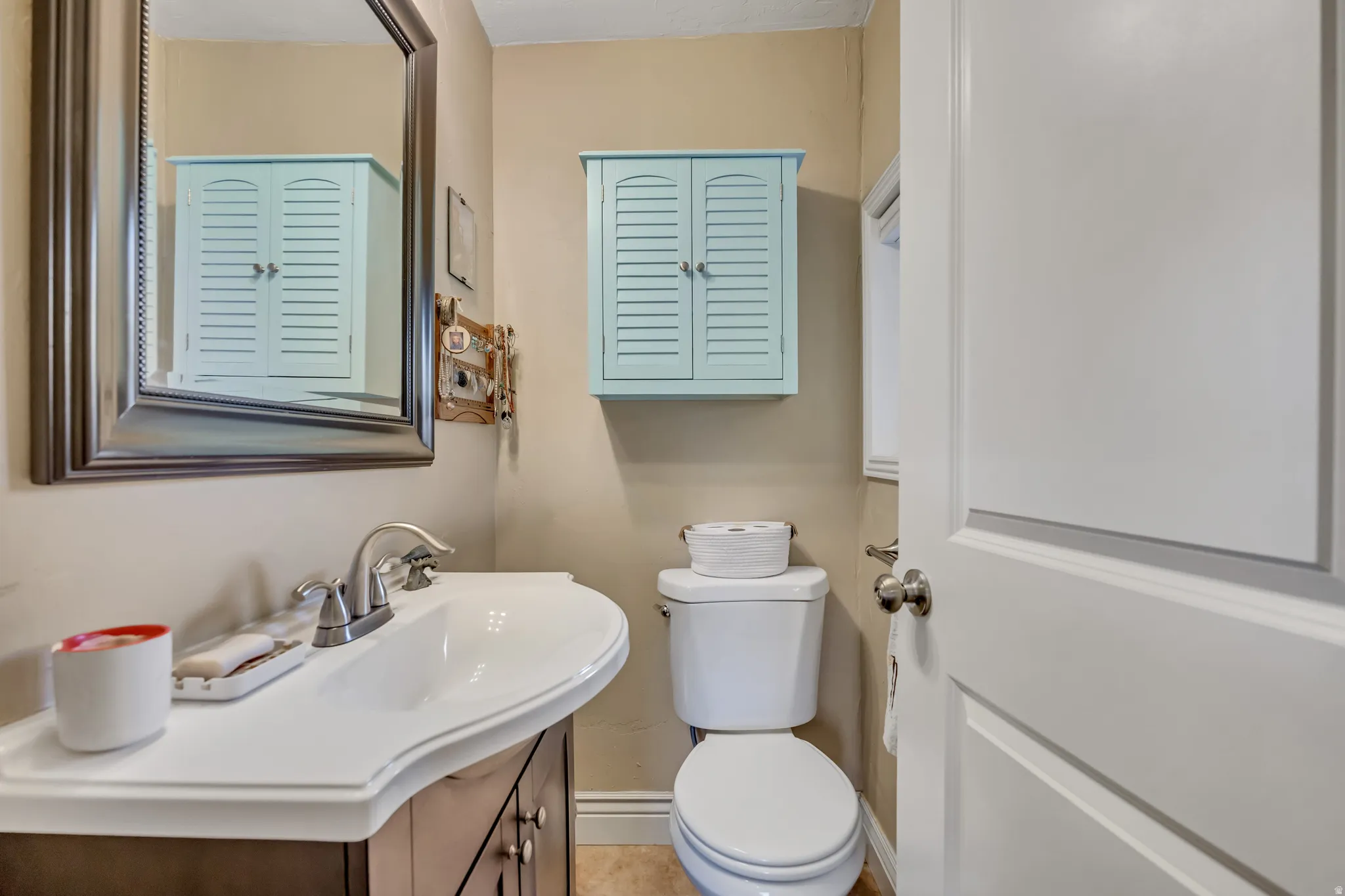 Bathroom featuring a white vanity with an integrated sink, brushed nickel faucet, and a framed mirror