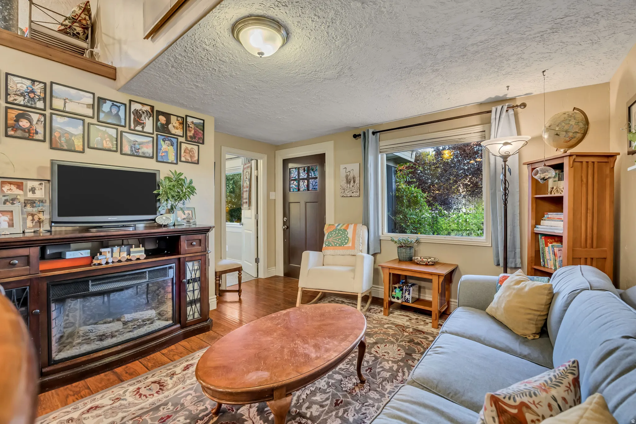 Living area featuring wood-finish flooring and a built-in media console with an electric fireplace insert