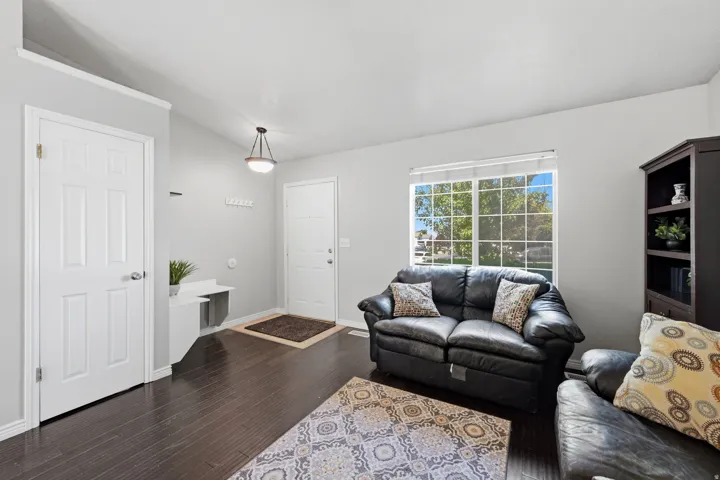 Spacious living area featuring dark wood-finish flooring, a large window with natural light, and light gray wall paint