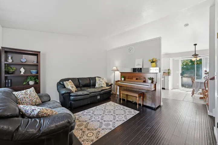 Living area featuring dark wood-finish flooring, light-toned walls, and a built-in partial wall