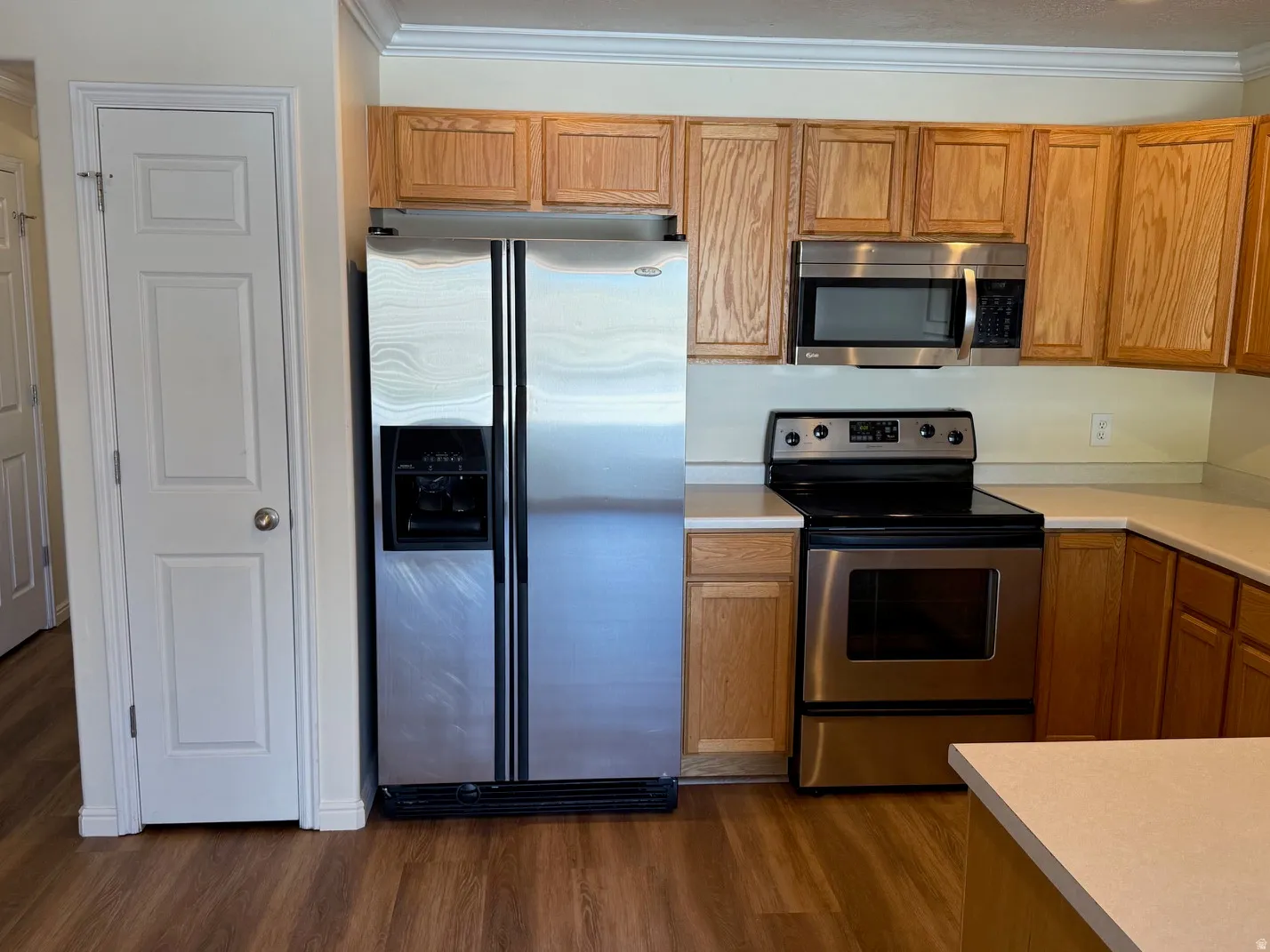 Kitchen featuring stainless steel appliances, light wood cabinetry, light-toned countertops, and wood-finish flooring