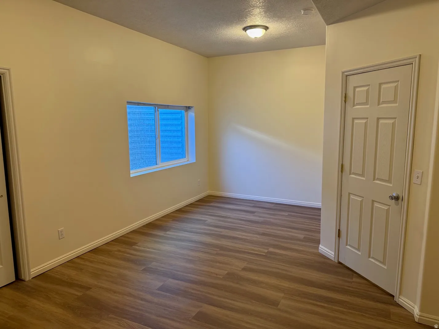 Basement bedroom featuring wood-finish flooring, neutral wall tones, and white baseboards
