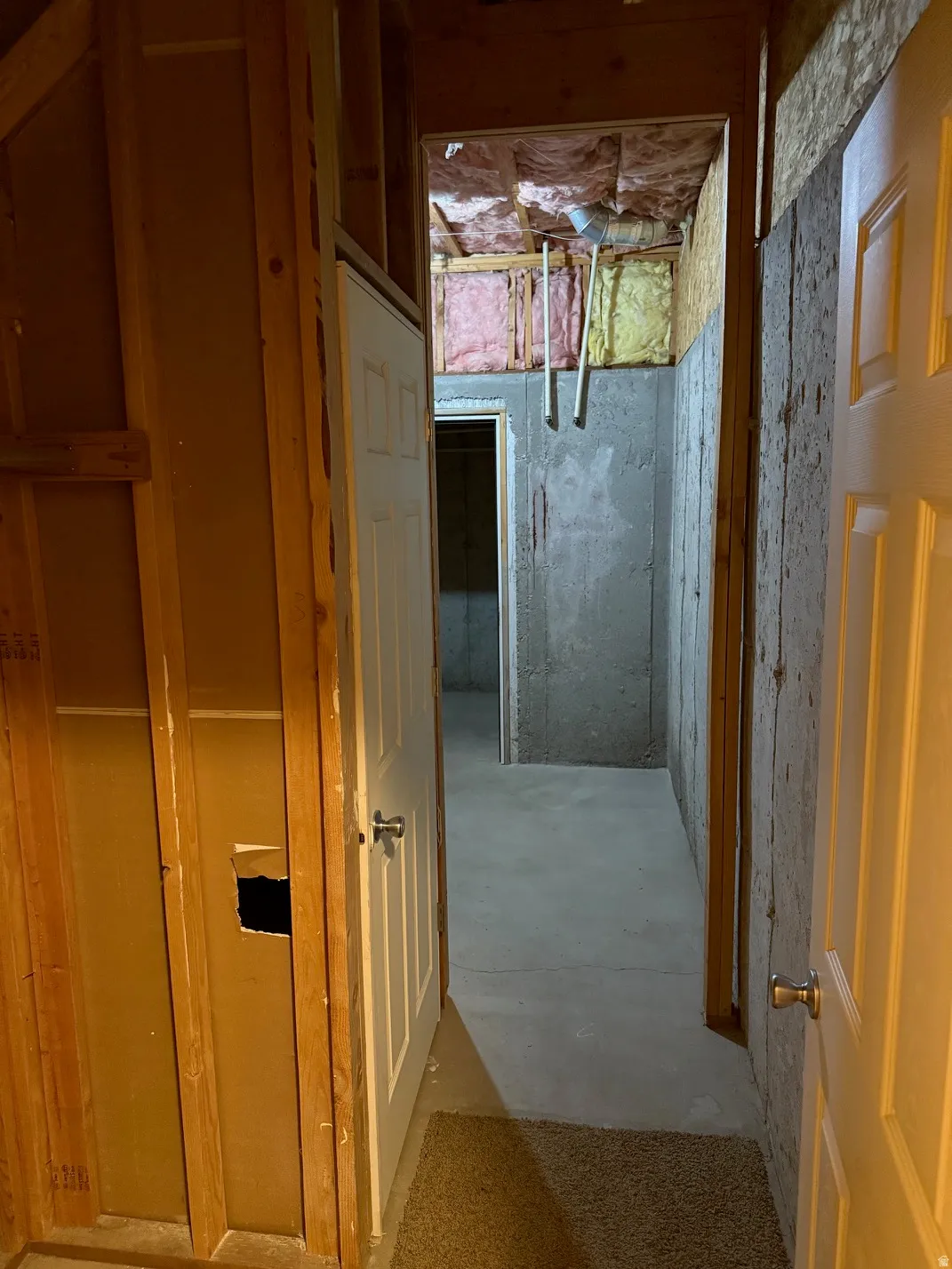 Unfinished basement area featuring exposed wood framing, concrete walls, and concrete flooring