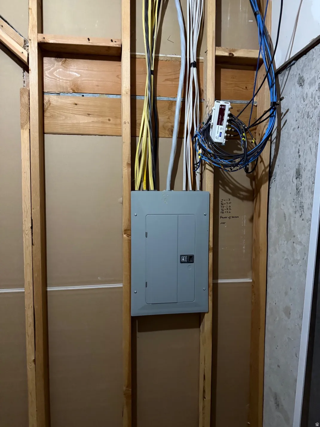 Electrical panel with exposed wiring within a framed wall structure