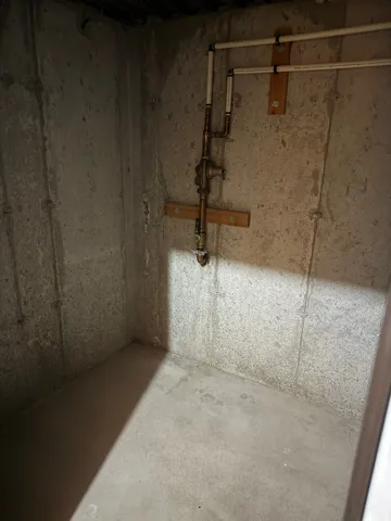 Concrete-walled utility space with exposed copper and PVC piping