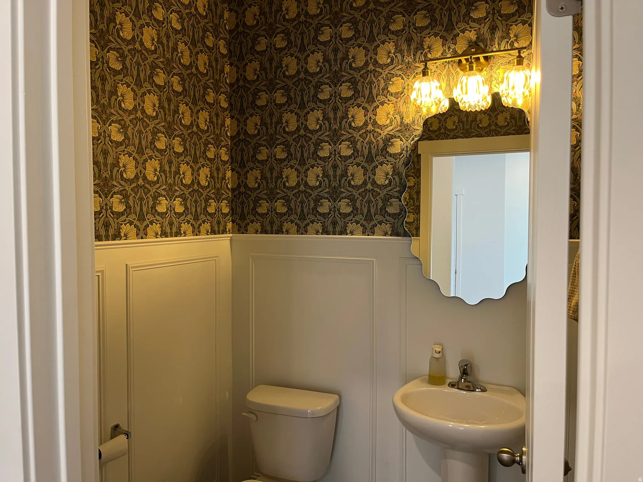 Powder bathroom with detailed molding, wallpaper and lighting.