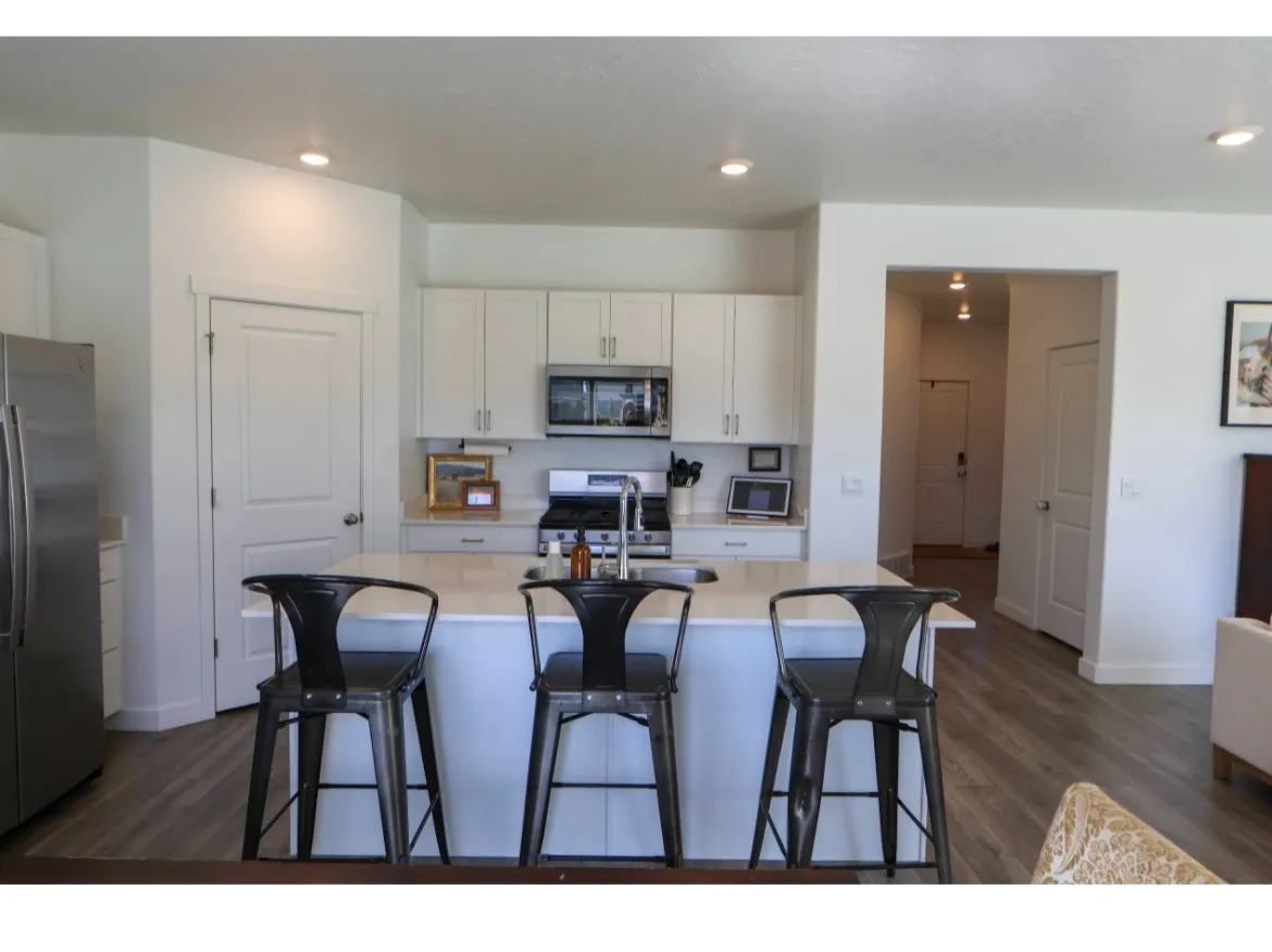 Open-concept kitchen featuring white cabinetry, Island with quartz countertops