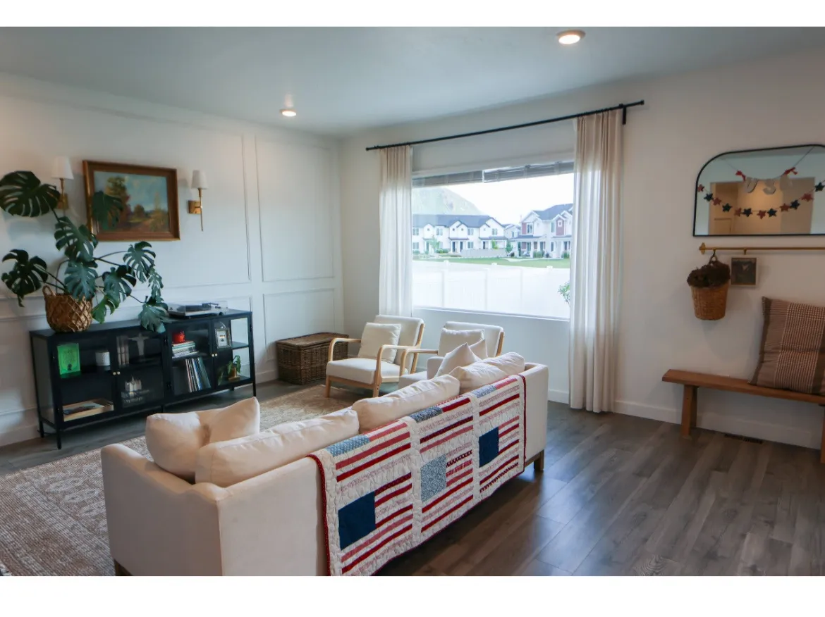 Living room with custom picture frame molding, large window and wood LVP flooring.
