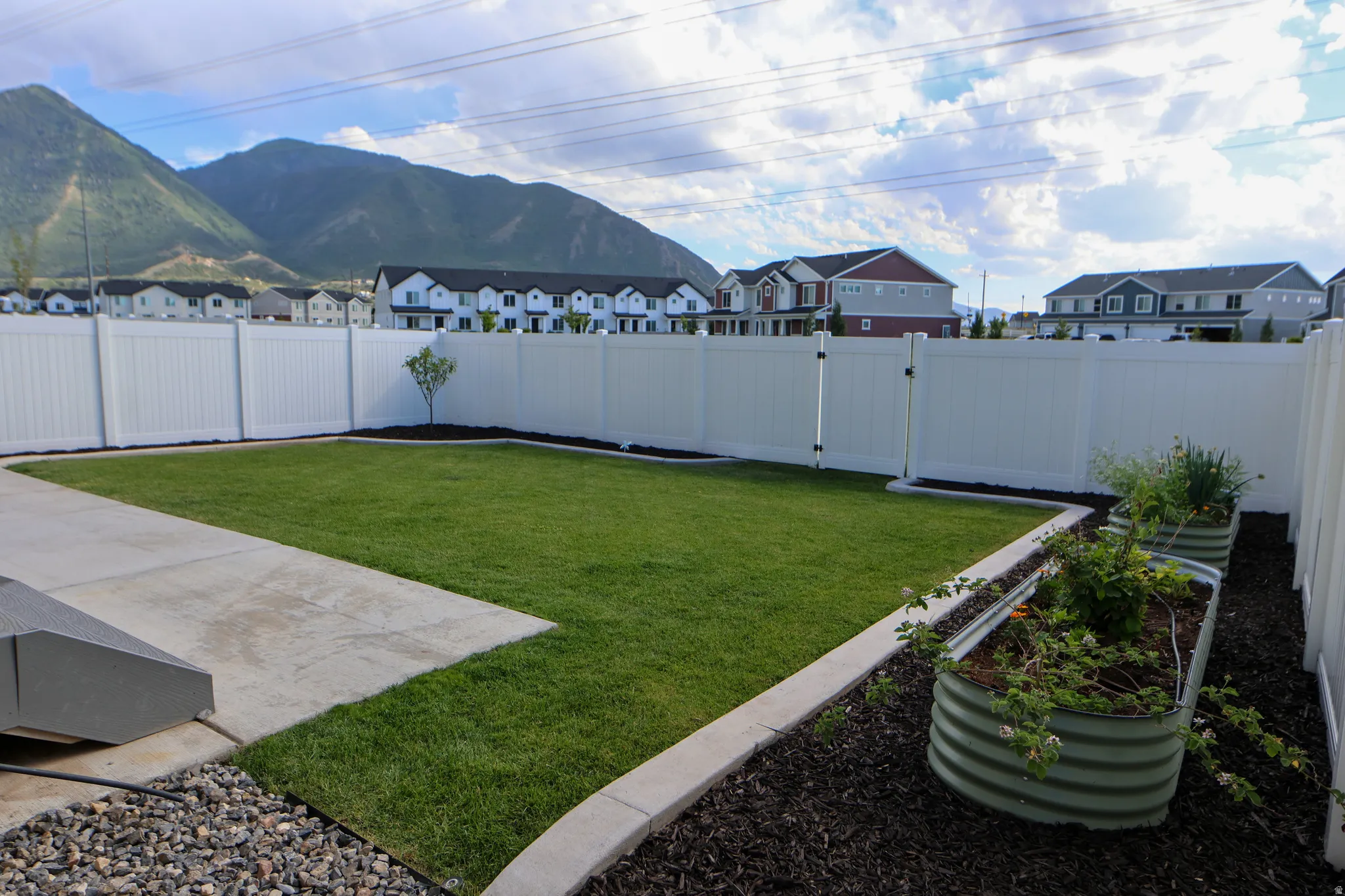 Fully fenced backyard, garden beds, grassy area and mountain views.