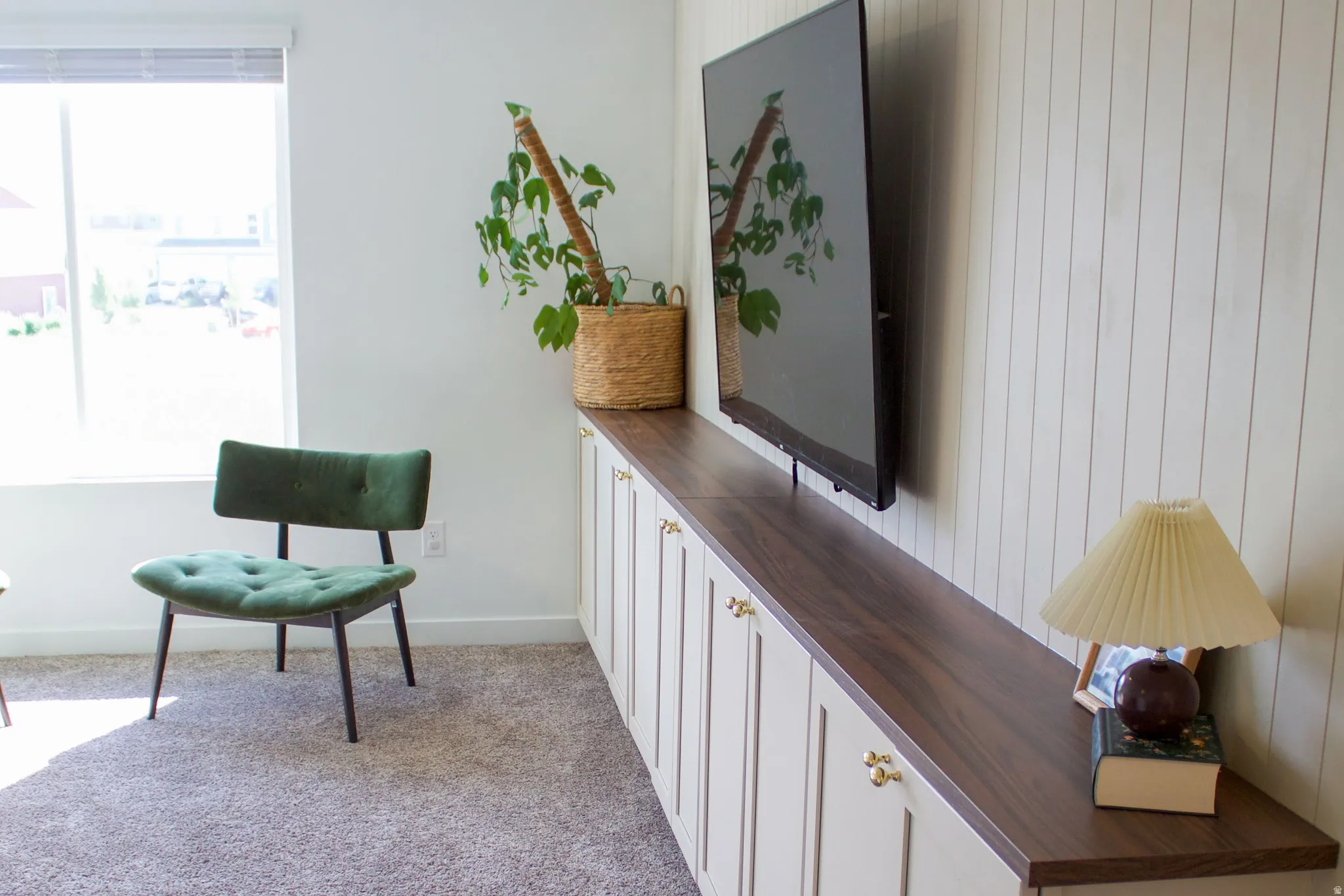 Built-in custom cabinetry with dark wood-finish countertop, vertical shiplap accent wall, and large window