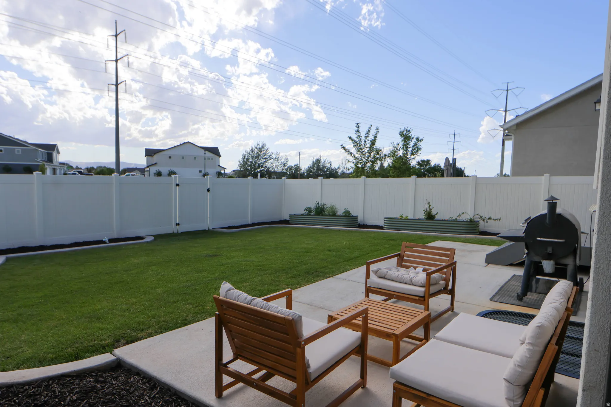 Fully fenced backyard, patio, garden beds and grass area.