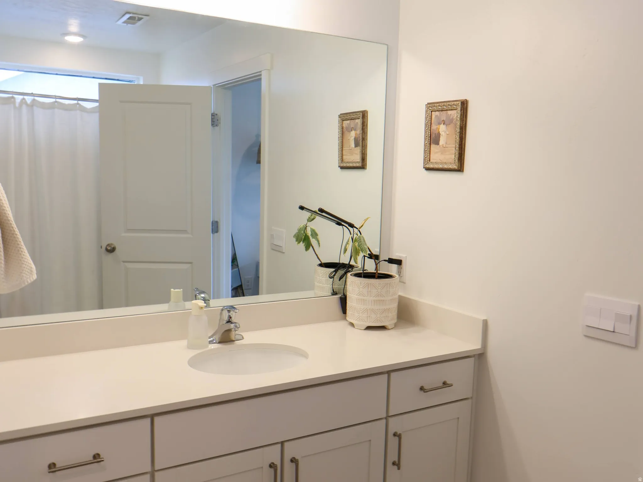 Primary bathroom with large vanity, quartz countertop, and white shaker-style cabinetry with brushed nickel hardware