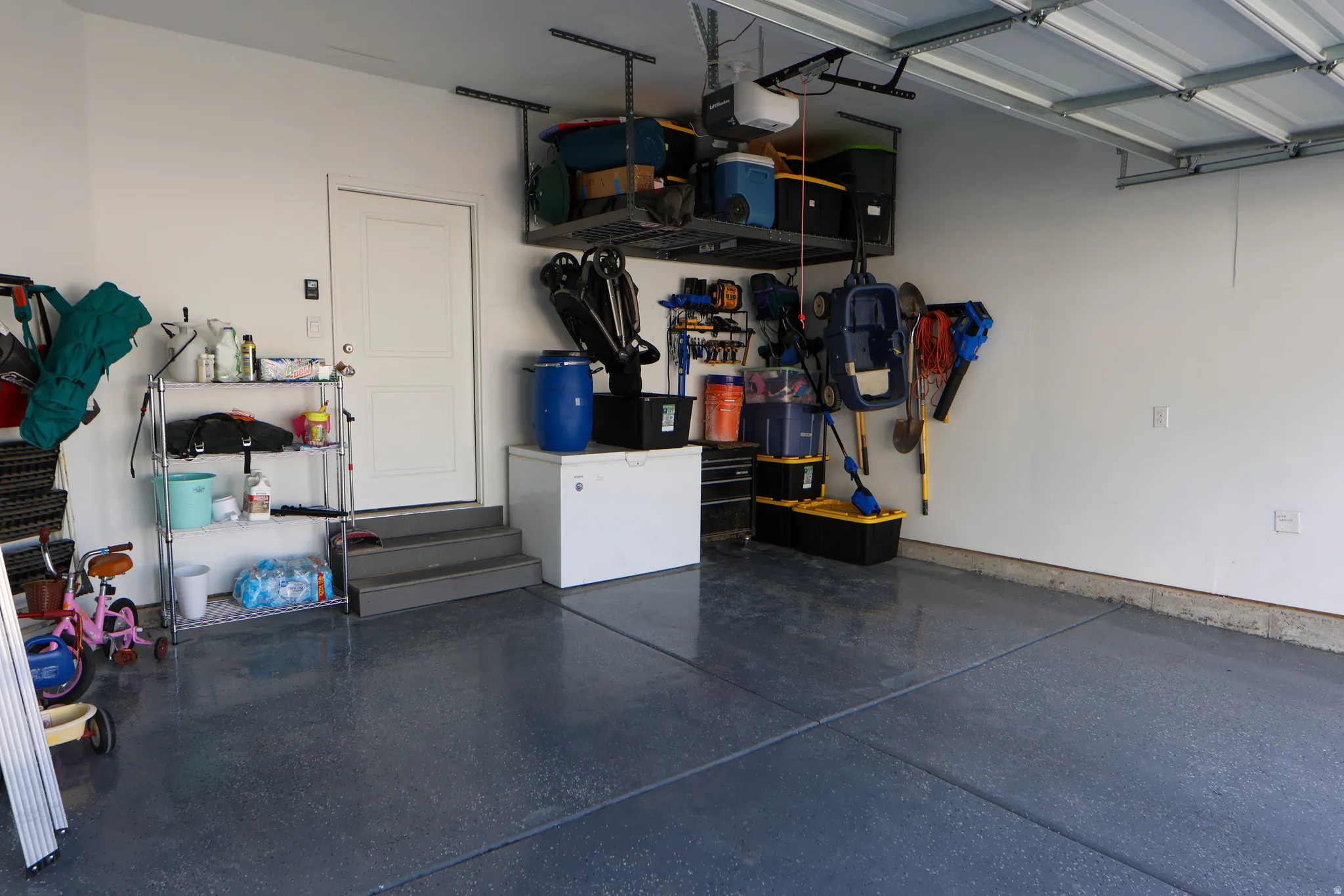 Spacious 2 car garage featuring an epoxy-coated floor and overhead storage racks.