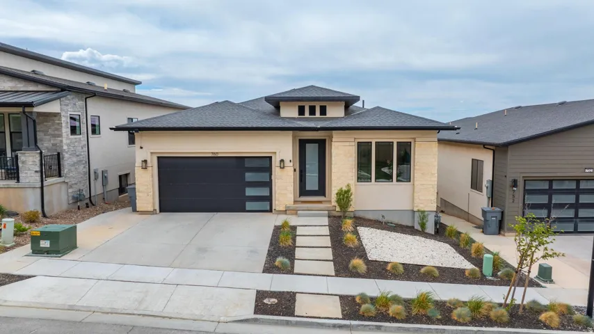 Contemporary exterior with a dark-pitched roof and light-colored stucco and stone veneer