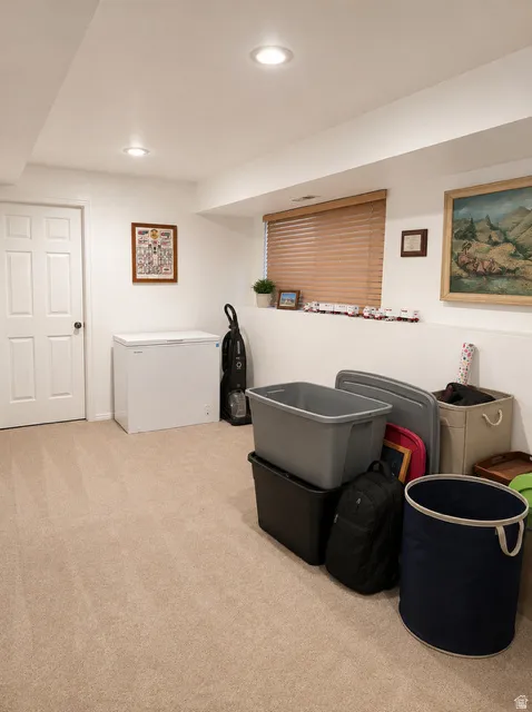Neutral tone carpeting with recessed lighting and a window featuring wood-finish blinds
