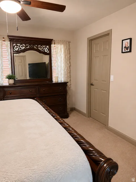 Carpeted bedroom with a ceiling fan