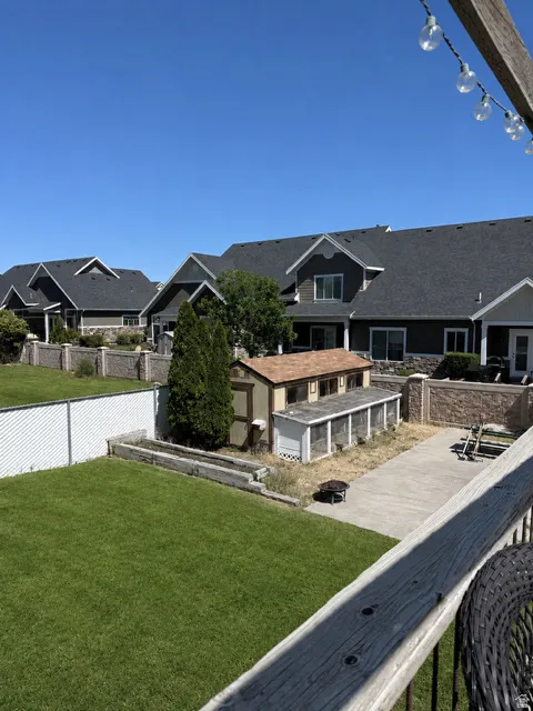 Spacious backyard featuring a manicured lawn, concrete patio, and a dedicated chicken coop structure