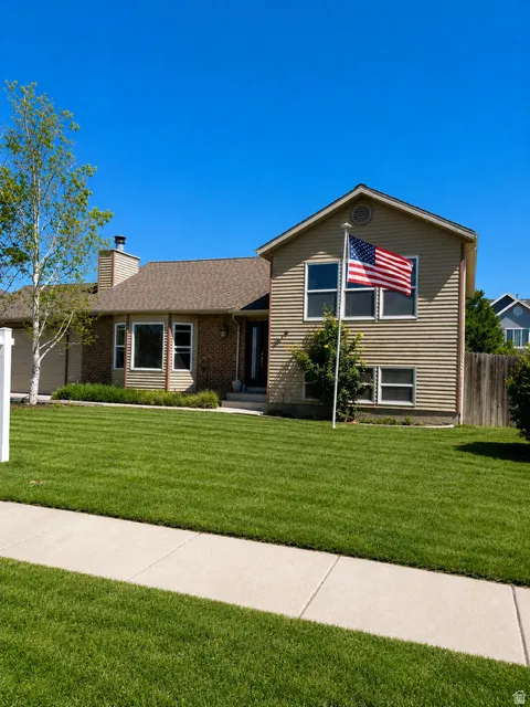 Traditional-style residence featuring a two-tone exterior with brick and horizontal siding, a gabled roof, and a prominent front lawn